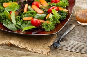 Healthy green salad on dark plate with rustic wooden boards
