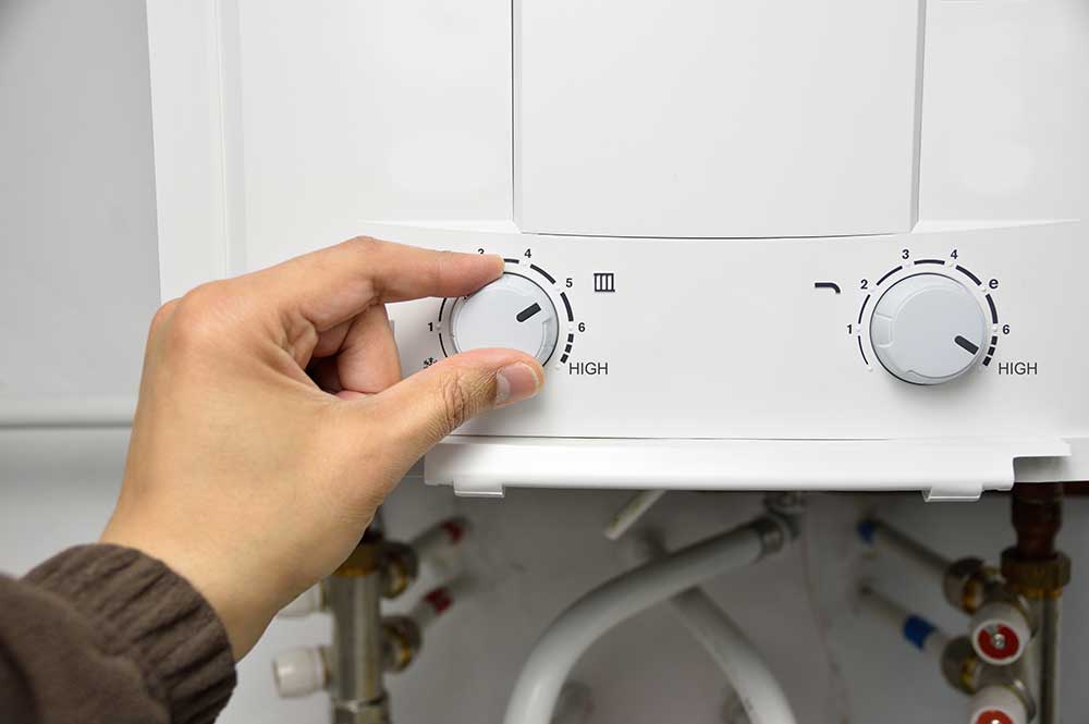 hand adjusting temperature on tankless water heater